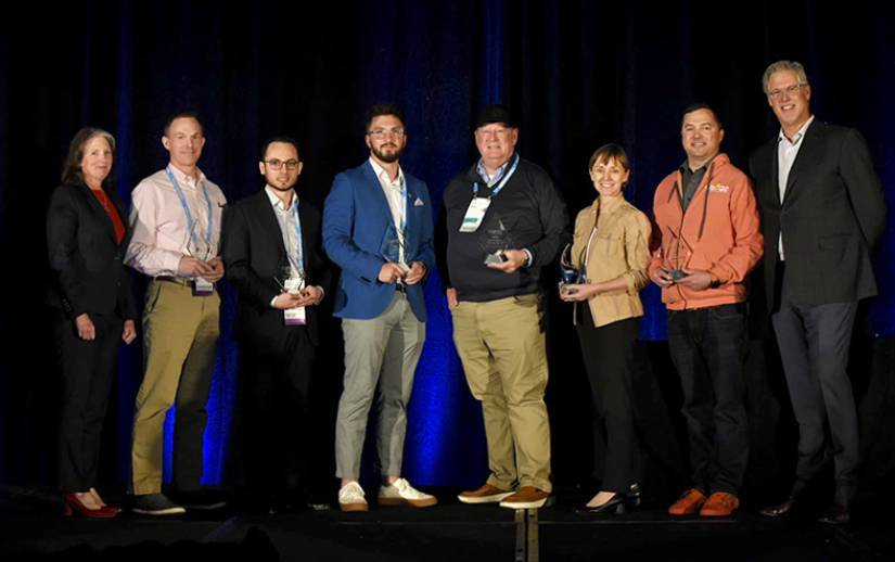 A group of people standing on a stage with awards.