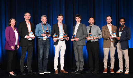 Continue reading about Eight people stand on a stage while holding awards.