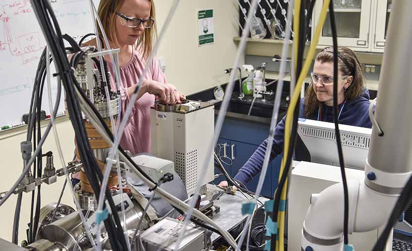 Two women working surrounded by laboratory equipment.