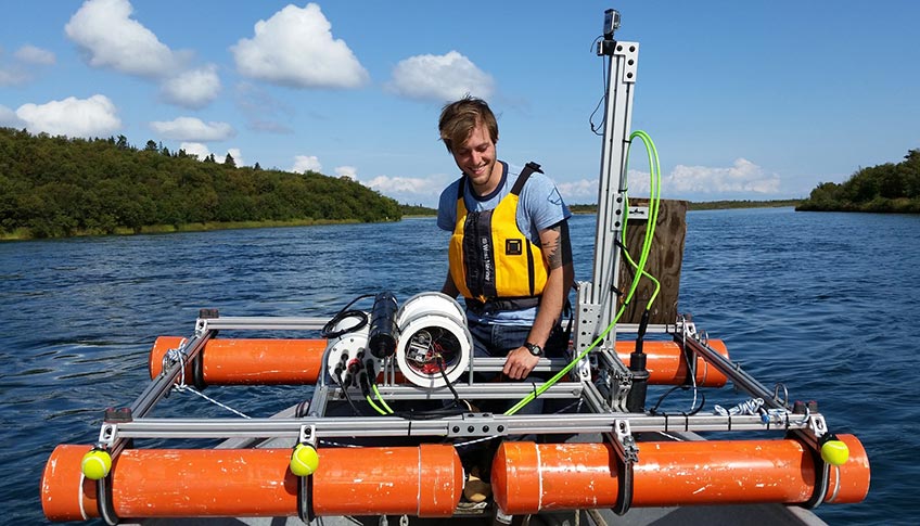 A young man prepares a flotational device from a river raft.