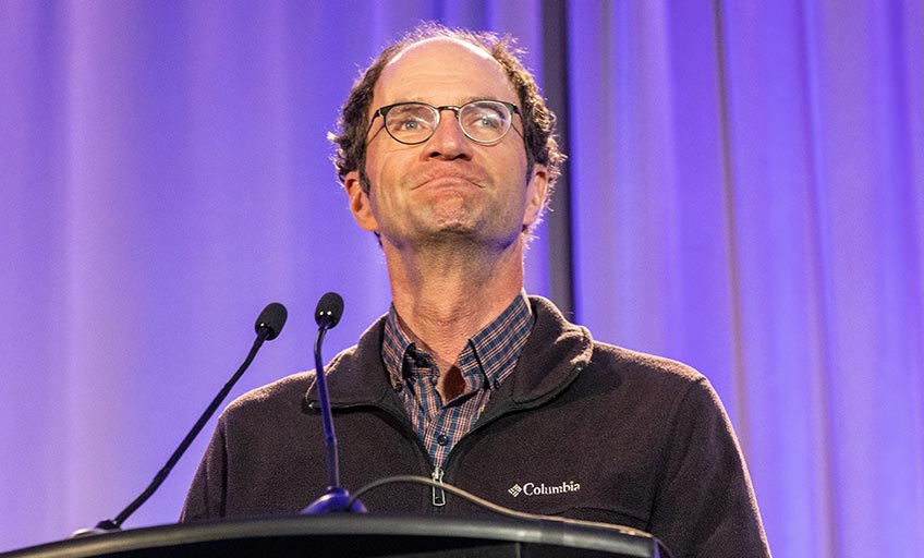 Man smiling in front of a podium. 