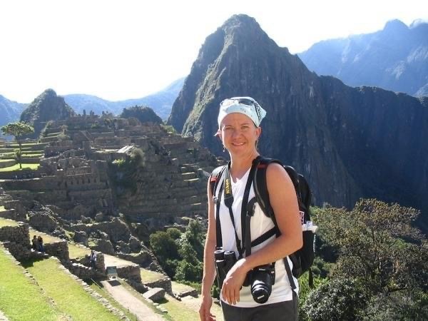 Photo of a woman with cameras around her neck and a big smile on the way up to Machu Picchu in Peru.
