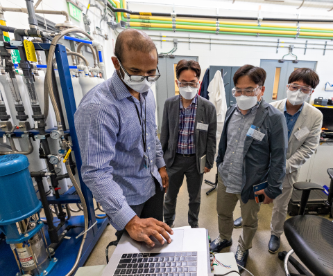A man operates a laptop computer in a lab while three other people watch