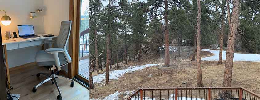 A chair and a desk with a laptop next to a view of a deck and a backyard with evergreen trees