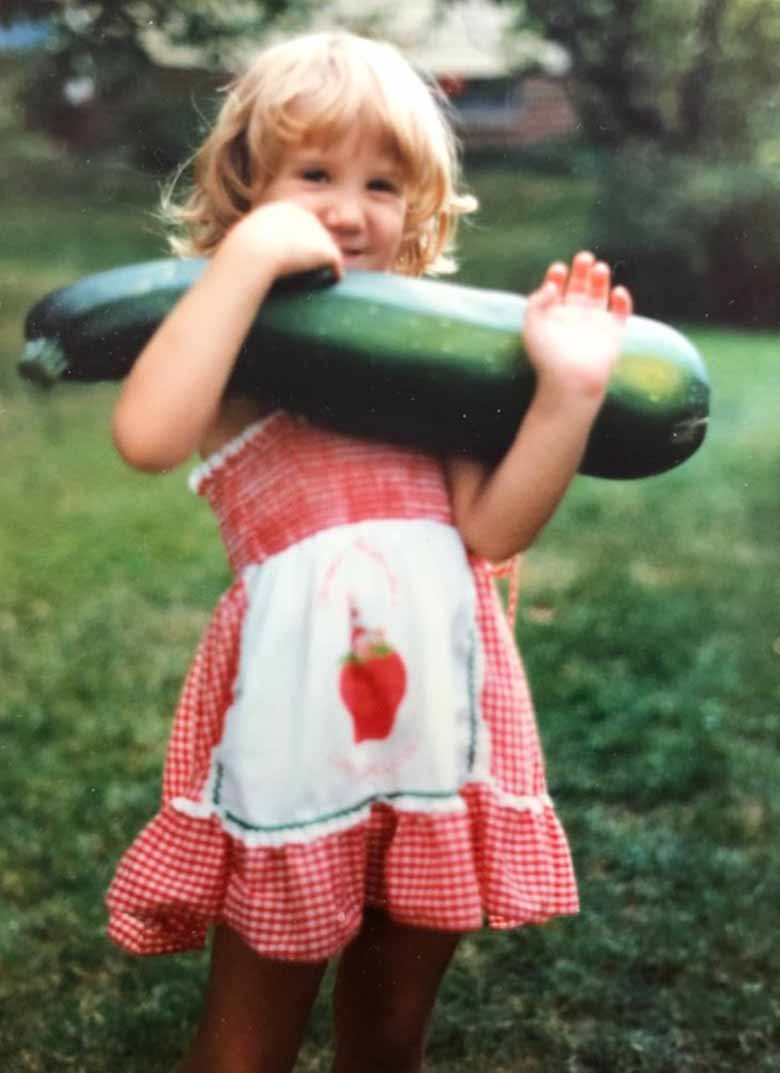 A child holding a very large zucchini