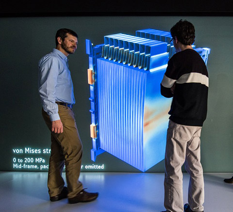 Photo of two men talking in front of a visualization screen
