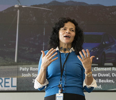 Photo of a woman speaking in front of a projection screen