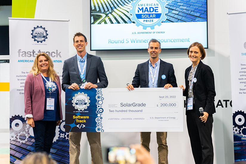 A group of four people on stage holding a big check.