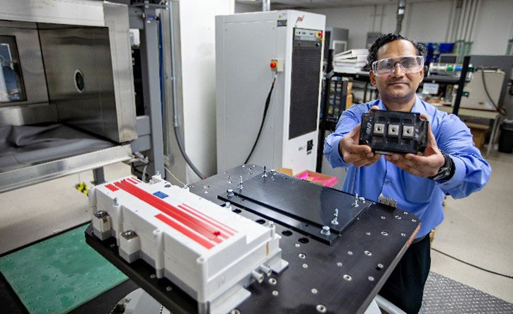 A researcher in a lab holding a device.