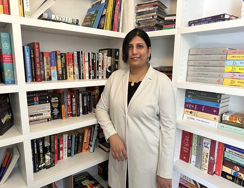 Mou Paul leaning on a bookcase.