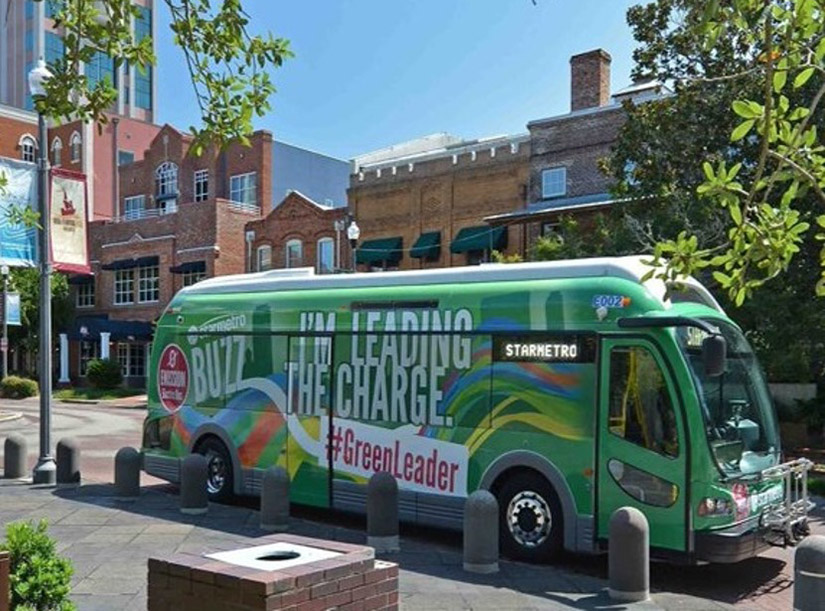 A bus on the street of Tallahassee that says I'm leading the charge and #greenleader