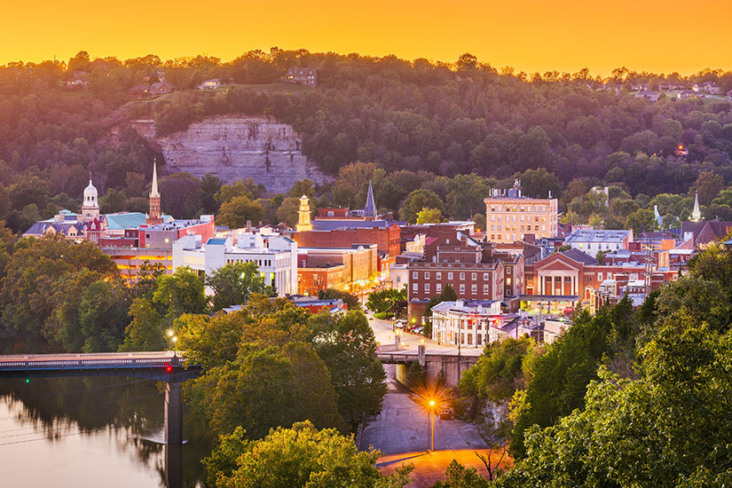 The buildings of downtown Frankfort, Kentucky, showing the rock cliff that looks over them, as the sun sets.