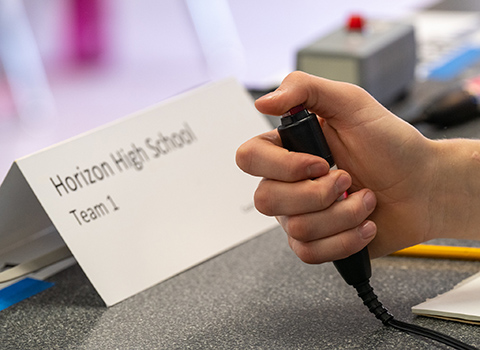 A hand holds a buzzer.