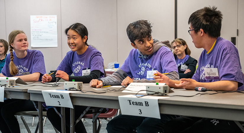 Five students deliberate at a table. 