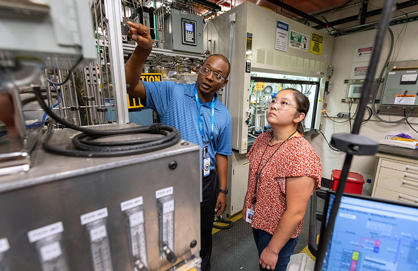 Two people examine equipment in a lab.