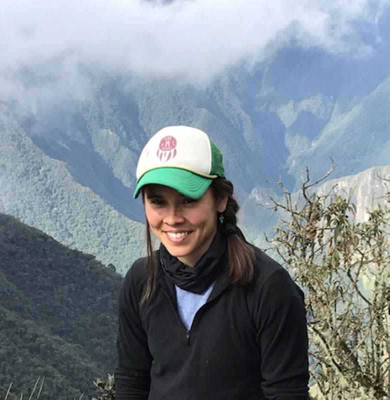 Stephanie Redfern with clouds, foliage, and steep mountains in the background.