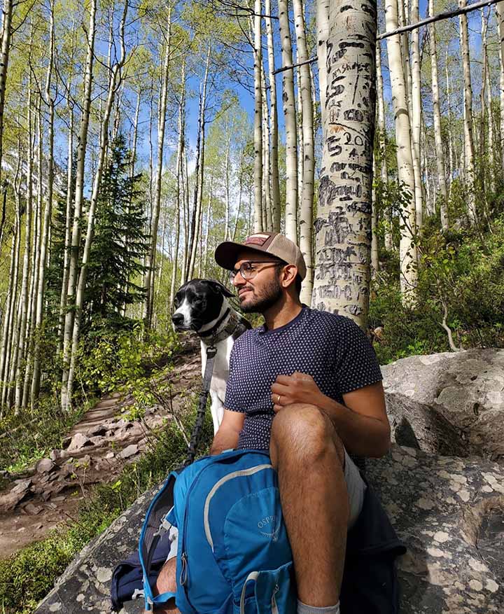 Man and dog outside in a wooded area.