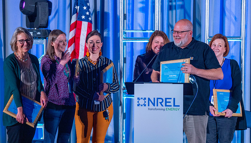 A group of people stand on stage accepting awards.