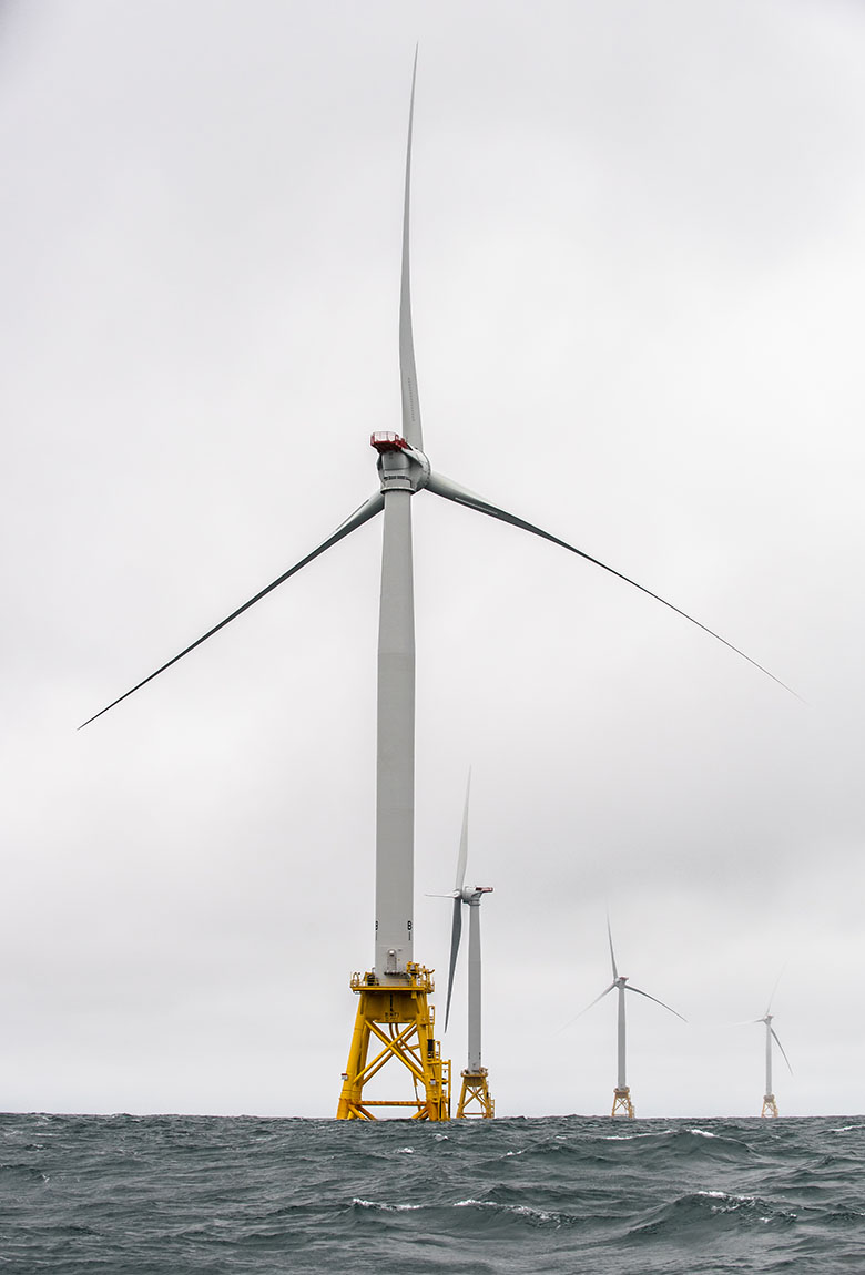 A group of offshore wind turbines rise over the ocean