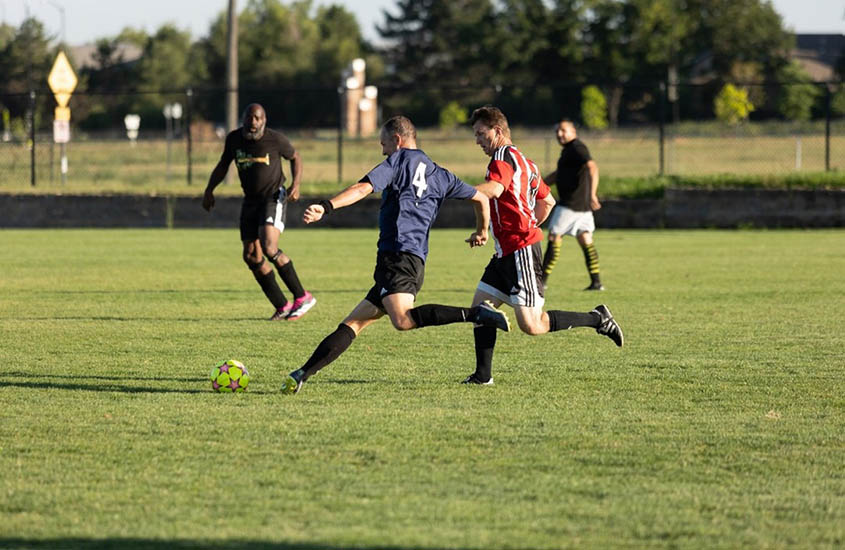 Two men playing soccer while two other men look on