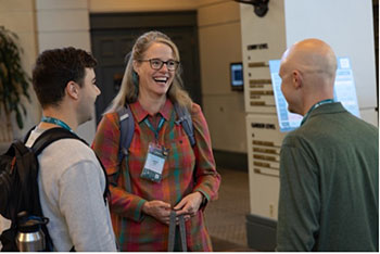 A group of conference attendees stand together and talk. 