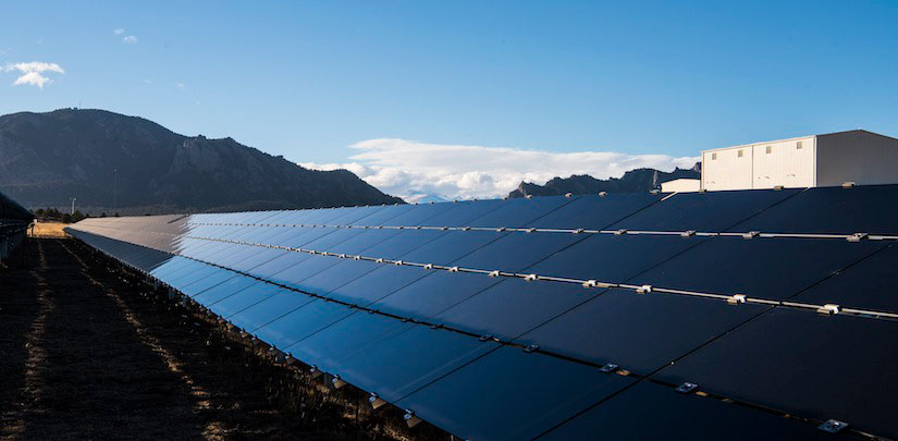 A row of black, reflective CdTe solar panels diminishes into the far distance.