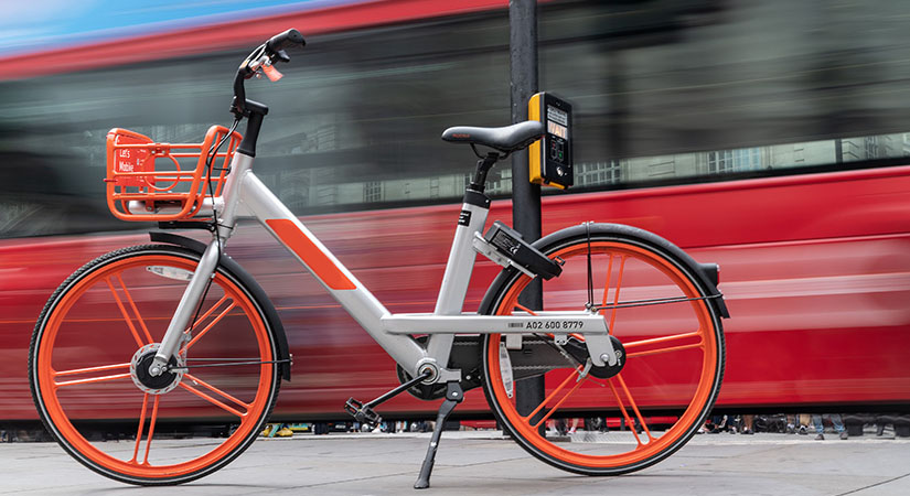 An electric bike sitting in front of a moving train.