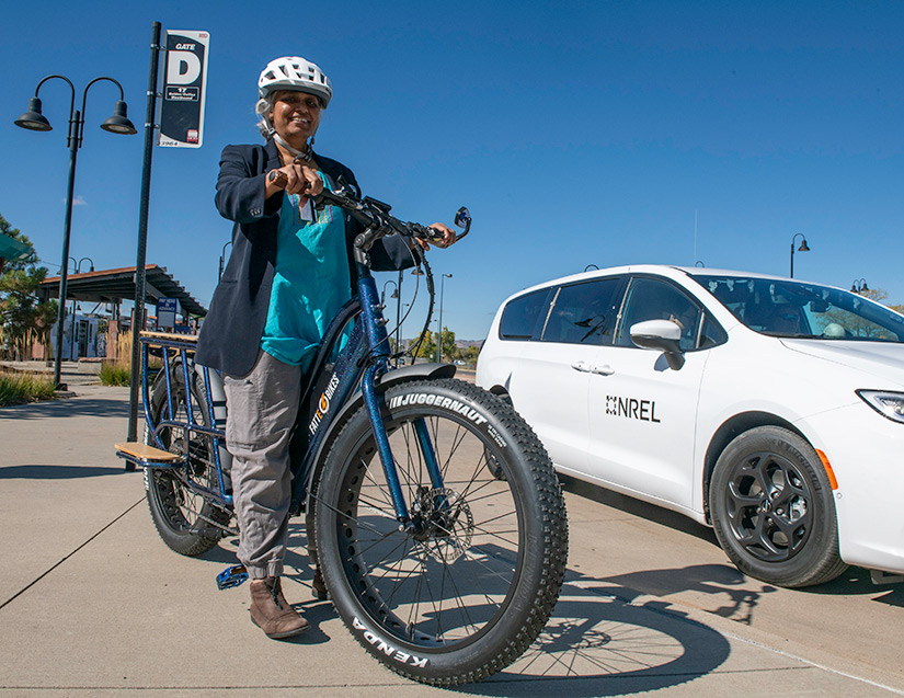 Photo of a woman standing in a parked position on a bike next to a car.