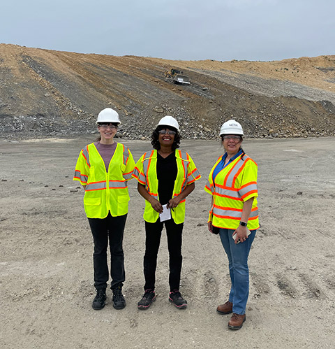 Three women standing in a field of gravel