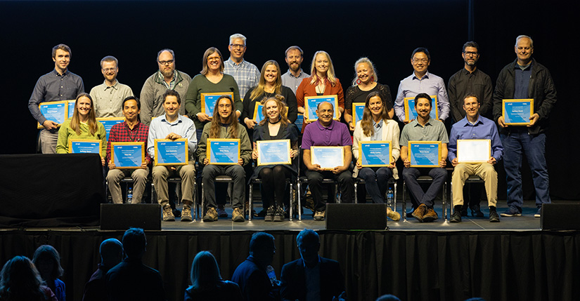 Rows of people holding awards sit on a stage.