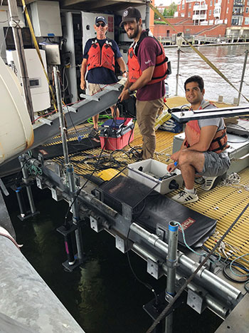 Three researchers on a platform next to the water
