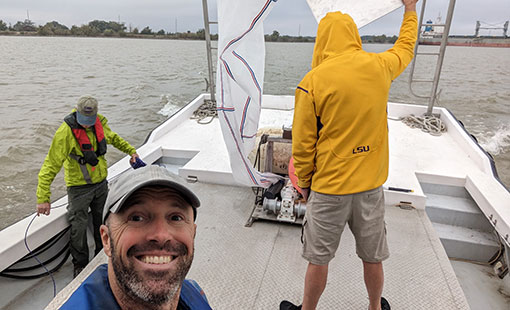 Three people working on a boat in the ocean
