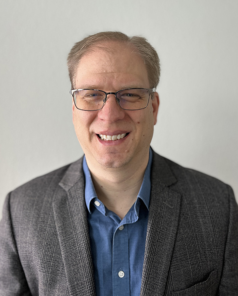 A person wearing glasses smiling.