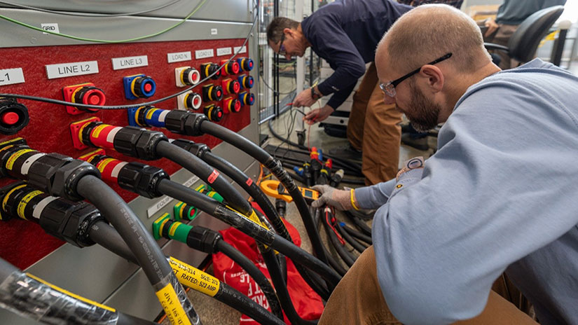 People leaning down to examine thick electrical cables