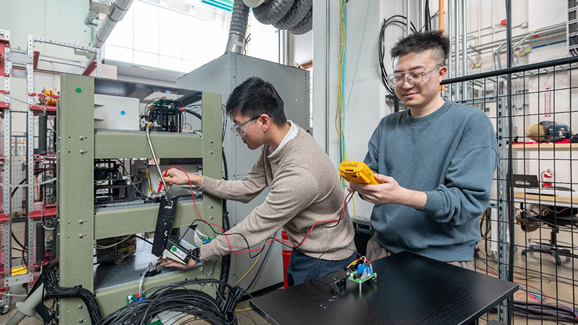 Two people wearing safety goggles handling electronics