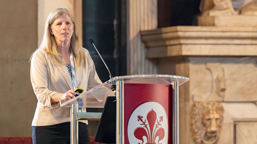 Amy Robertson stands speaking at a podium