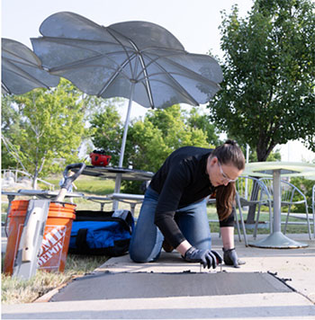Ana Aday smoothing a poured slab of concrete in a sidewalk