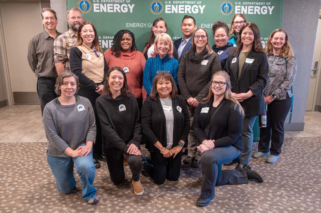 16 people pose in front of a U.S. Department of Energy banner.