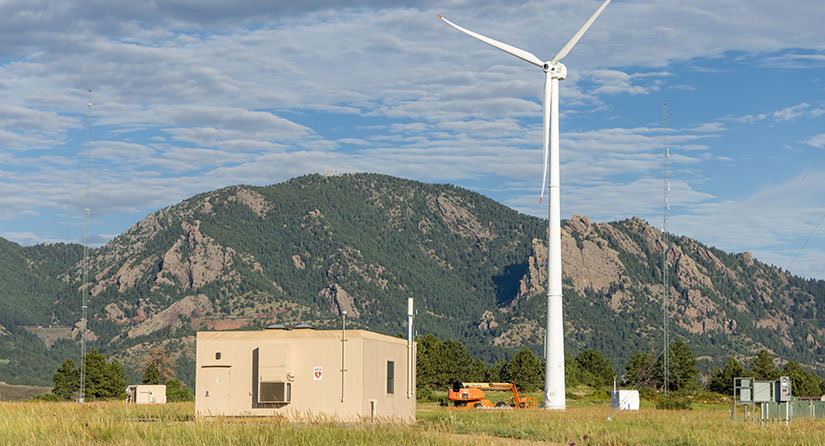 Wind turbine stands in a field next to an out building