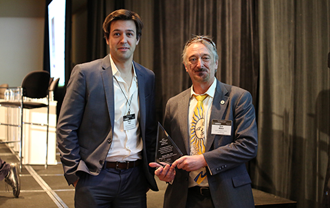 Eric Miller presents an award plaque to Shaun Alia