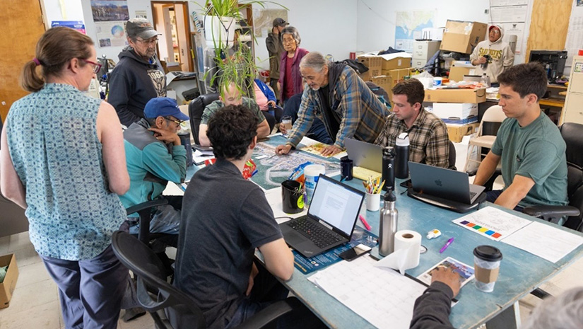 Nine people pose with a certificate in a community room.