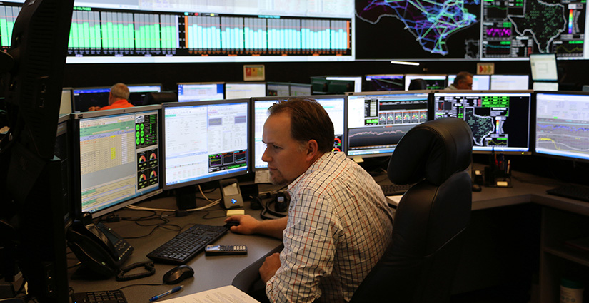 Photo of a person sitting in the control room of an electric utility.