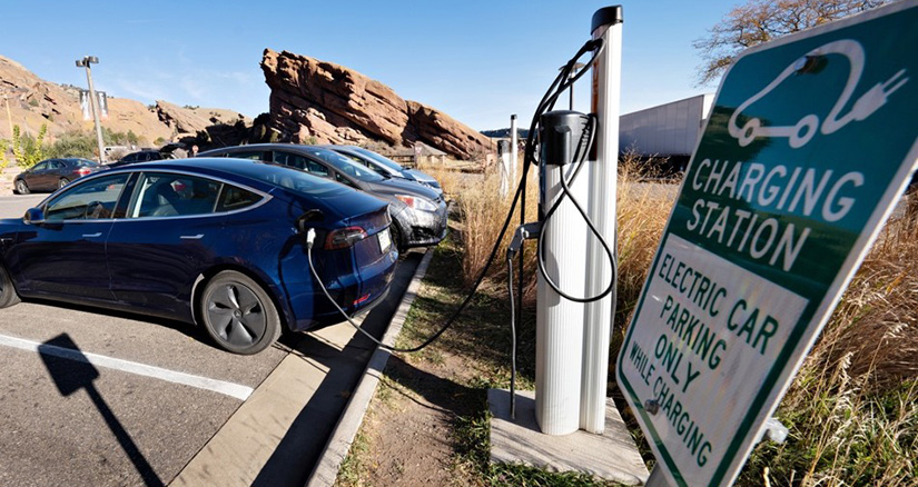 Electric vehicles charge at charging stations in a parking lot.