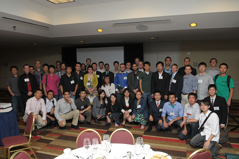 An older photograph of many researchers standing together in a carpeted conference room.