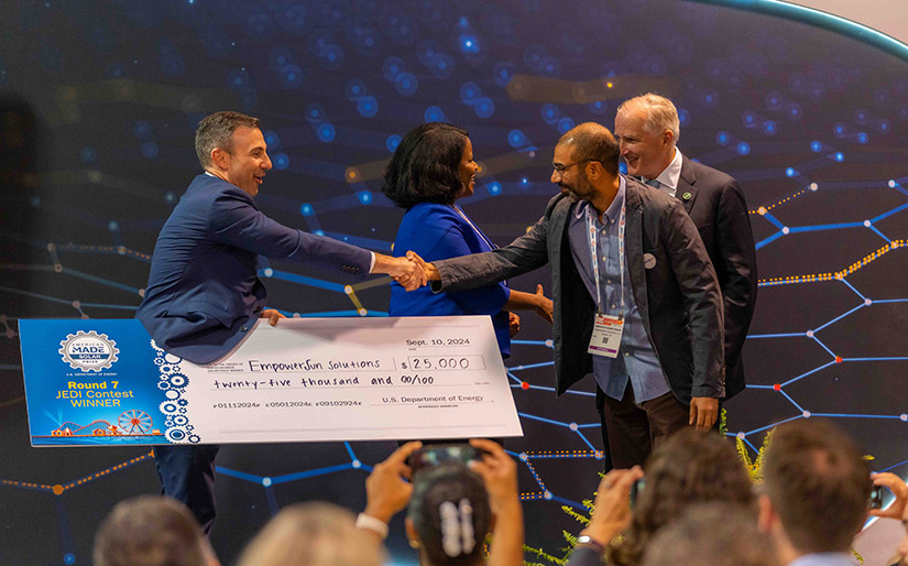 A person holding a giant check shaking another person's hand.