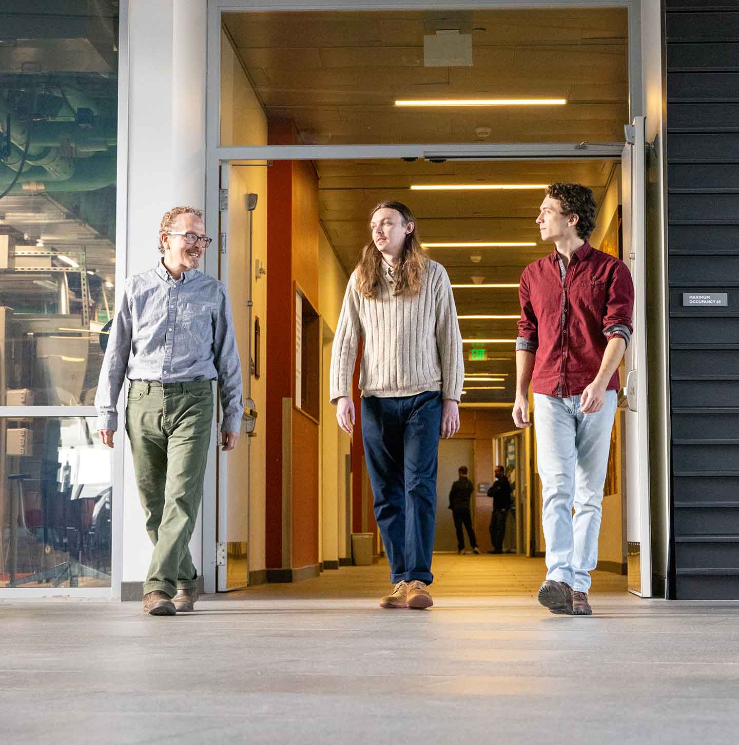 Three people talking as they exit a hallway