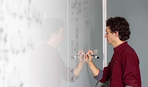 Continue reading about Scientist writing on a whiteboard as part of his research process into quantum computing benchmark problems