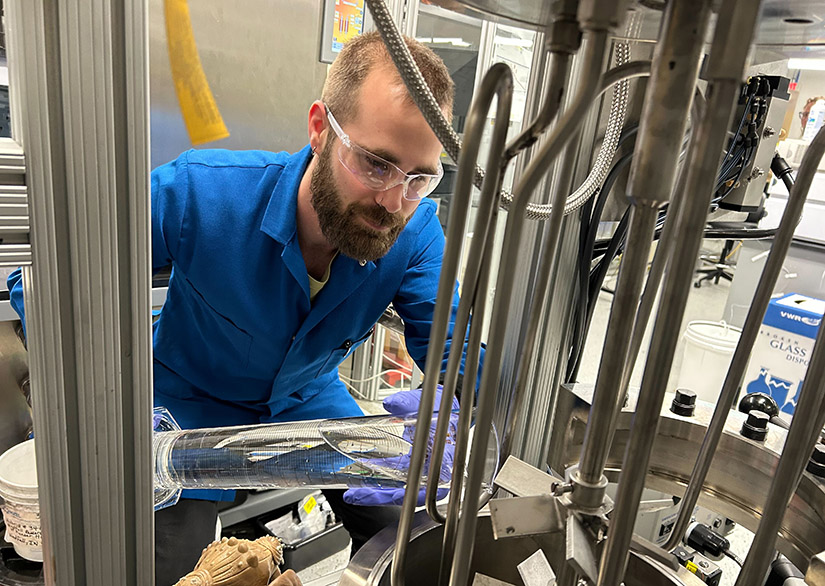 A researcher pours a liquid into a machine in a lab.
