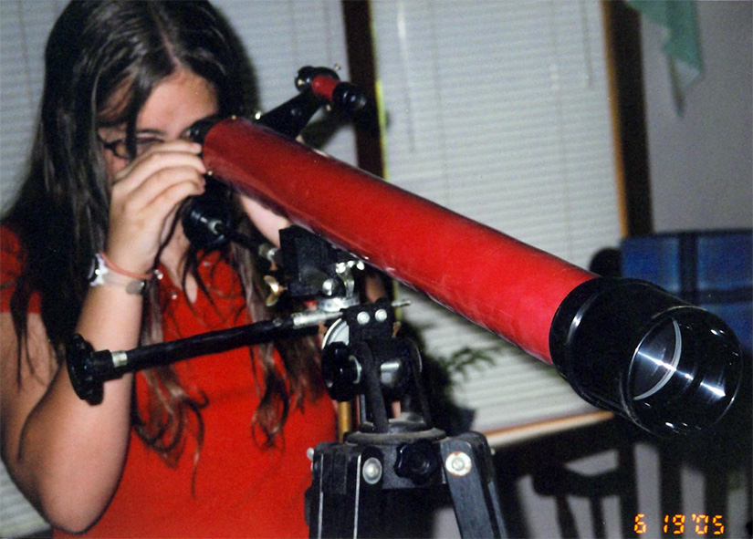 A teenager looks through a telescope.