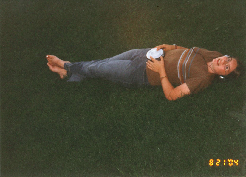 A girl laying in the grass with a portable CD player and headphones.